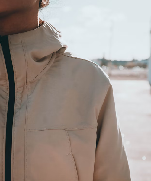 Person klädd i beige jacka, endast höger bröstkorg synlig